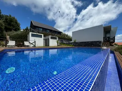 a large blue swimming pool in front of a house at ModuLAR in Calheta