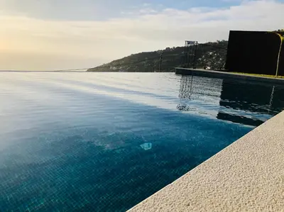 a swimming pool with blue water in the foreground at Villa Palheiros in Arco da Calheta