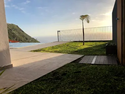 a walkway with a fence and a palm tree at Villa Palheiros in Arco da Calheta