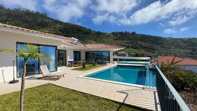 a villa with a swimming pool and a mountain at Villa Palheiros in Arco da Calheta
