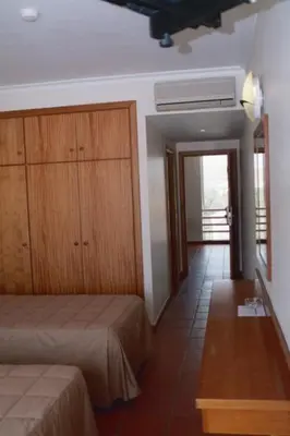 a bedroom with two beds and a wooden cabinet at Areia Dourada in Porto Santo