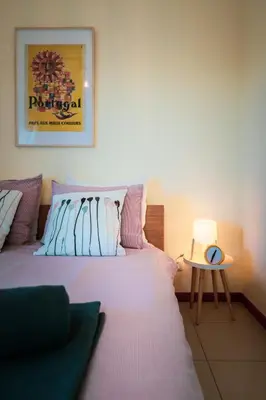 a bedroom with a bed and a table with a clock at Casa Laranja, Aromas Burgau in Burgau