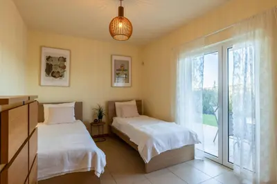 two beds in a room with a window at Casa Laranja, Aromas Burgau in Burgau
