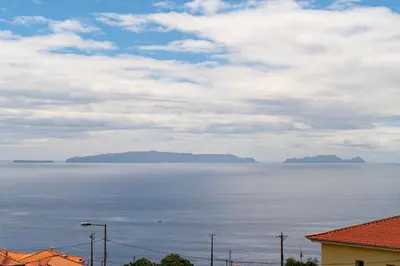 a view of the ocean with mountains in the distance at Caniço V by An Island Apart in Caniço