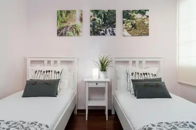 two beds in a white room with paintings on the wall at Caniço V by An Island Apart in Caniço