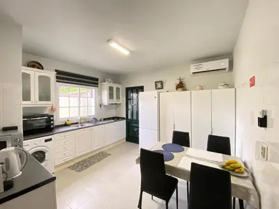 a kitchen with white cabinets and a table and chairs at Casa do Arco in Arco da Calheta