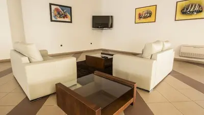 a living room with two white chairs and a tv at Hotel Santa Maria in Vila do Porto