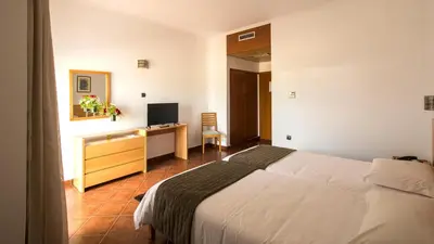 a bedroom with a bed and a desk with a television at Hotel Santa Maria in Vila do Porto