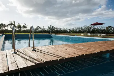 a swimming pool with a wooden dock and an umbrella at Hotel Santa Maria in Vila do Porto