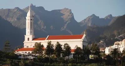 a large white church with mountains in the background at Atlantic Pearl America apartment by Holiday Rental Madeira in Funchal