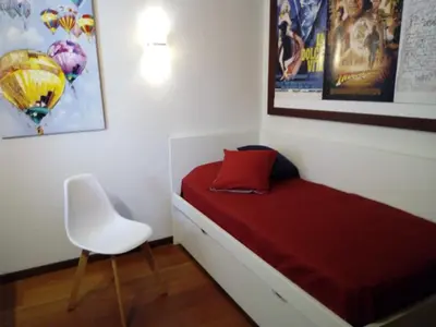a small bedroom with a bed and a white chair at Un Balcon Sur La Mer in Funchal
