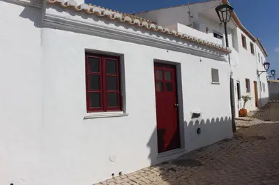 a white building with red windows and a red door at Casa Marreiros Holiday Home in Vila do Bispo