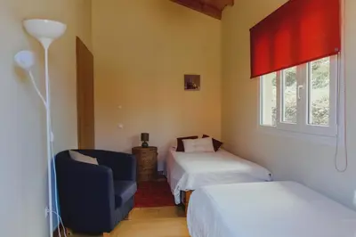 a bedroom with two beds and a chair and a window at Sunrise House in Ponta Delgada