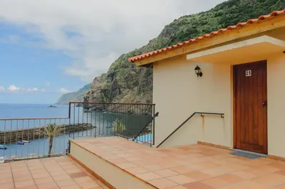 a house with a balcony with a view of the ocean at Sunrise House in Ponta Delgada
