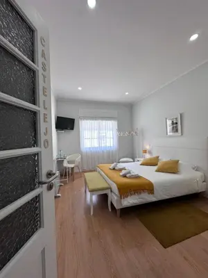 a bedroom with a large bed and a table at Ardmar B&B in Vila do Bispo
