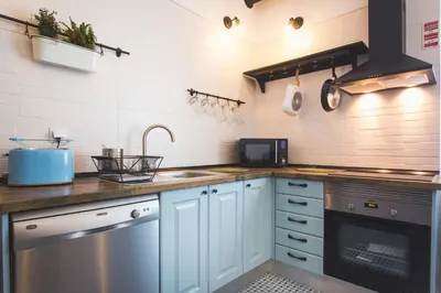 a kitchen with blue cabinets and a sink and a dishwasher at Ardmar B&B in Vila do Bispo