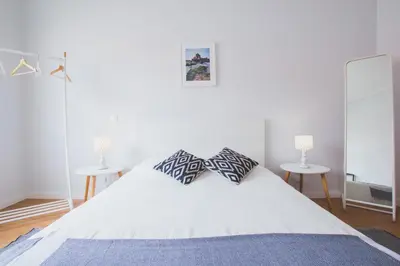 a bedroom with a white bed with two tables at Ardmar B&B in Vila do Bispo
