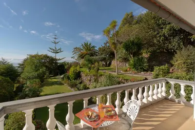 a table on a balcony with a view of a garden at Pool Villa with Botanical Garden in Funchal