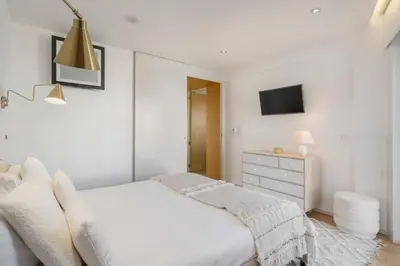 a white bedroom with a bed and a dresser at Baía I by An Island Apart in Funchal