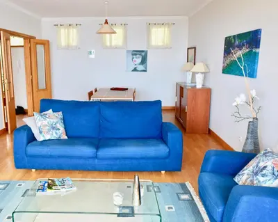 a living room with a blue couch and a table at Jardim do Arco 