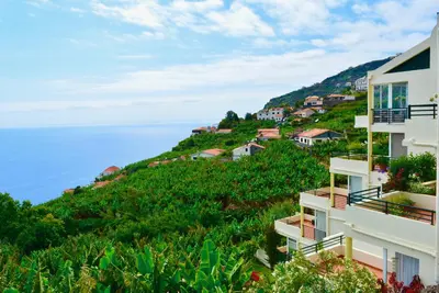 a building on a hill next to the ocean at Jardim do Arco 