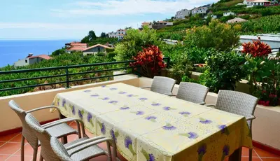 a table and chairs on a balcony overlooking the ocean at Jardim do Arco 