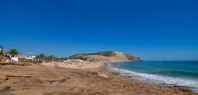 a beach with people sitting on the sand and the ocean at Luz Beach Luxury Apartment in Luz