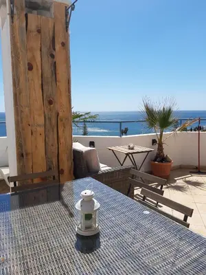 a table on a balcony with a view of the ocean at AMAZING PENTHOUSE- panoramic sea view & tikki bar on private terrasse in Luz