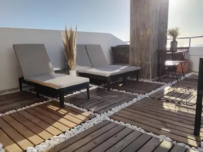 a patio with two chairs and a couch on a deck at AMAZING PENTHOUSE- panoramic sea view & tikki bar on private terrasse in Luz
