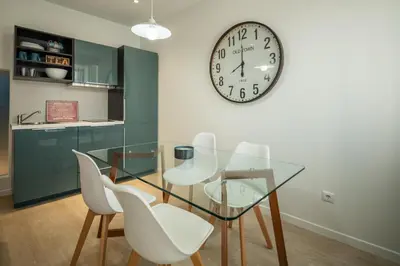 a dining room with a glass table and white chairs and a clock at BAYLEAF Apartments - Apartamento do Tempo in Funchal