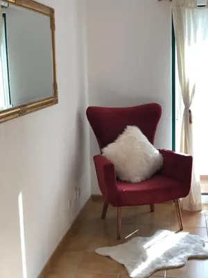 a red chair with a white pillow sitting in a room at Luz Paradise in Luz