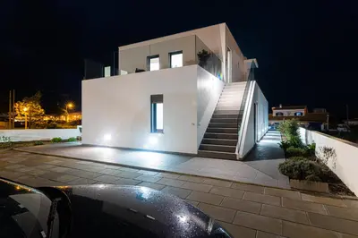 a large white house with stairs in front at night at Biscuttela Vicentina in Praia da Arrifana