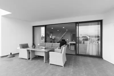 a living room with a table and chairs and glass doors at Biscuttela Vicentina in Praia da Arrifana