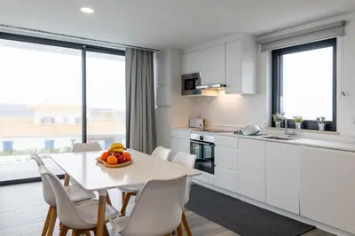 a kitchen and dining room with a table and chairs at Biscuttela Vicentina in Praia da Arrifana