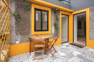 a table and chairs on a patio with a yellow wall at BAYLEAF Apartments - Casa D'Avó in Funchal