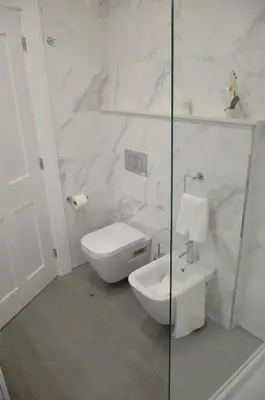 a white bathroom with a toilet and a glass shower at Edificio Charles 102 in Funchal