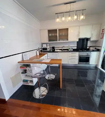 a kitchen with white cabinets and a wooden table at Marias sea cottage in Funchal
