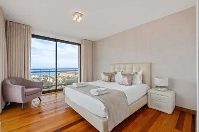 a bedroom with a white bed and a large window at Villa Beausoleil by Homie in Funchal