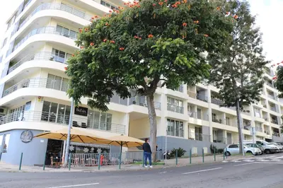 a man standing under an umbrella in front of a building at Uptown Madalenas in Funchal