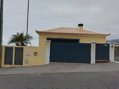 a house with a garage with a blue door at Sea View House in Ribeira Brava