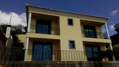 a yellow building with balconies and a fence at Sea View House in Ribeira Brava