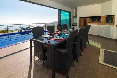 a dining room with a table and chairs and a balcony at Casa Lira in Arco da Calheta