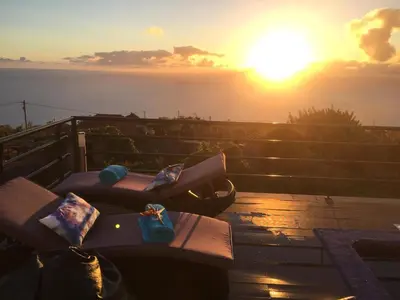 a view of the sunset from a balcony with benches at Casa Lira in Arco da Calheta