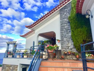 a villa with a staircase leading to a balcony at Casa Lira in Arco da Calheta