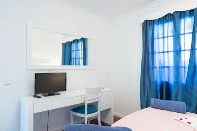 a bedroom with a desk with a computer and a blue chair at Casa Lira in Arco da Calheta