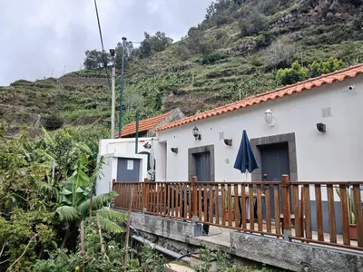 a house with a wooden fence and a mountain at casa da fajã in Funchal
