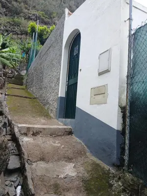 a small white building with a green door at casa da fajã in Funchal