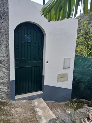 an entrance to a building with a green door at casa da fajã in Funchal