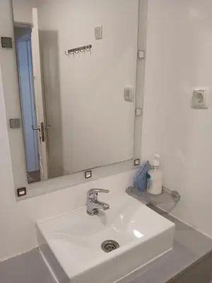 a white bathroom sink with a large mirror at casa da fajã in Funchal