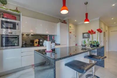 a kitchen with white cabinets and a counter with stools at Pérola - Madeira Inn Group in Funchal